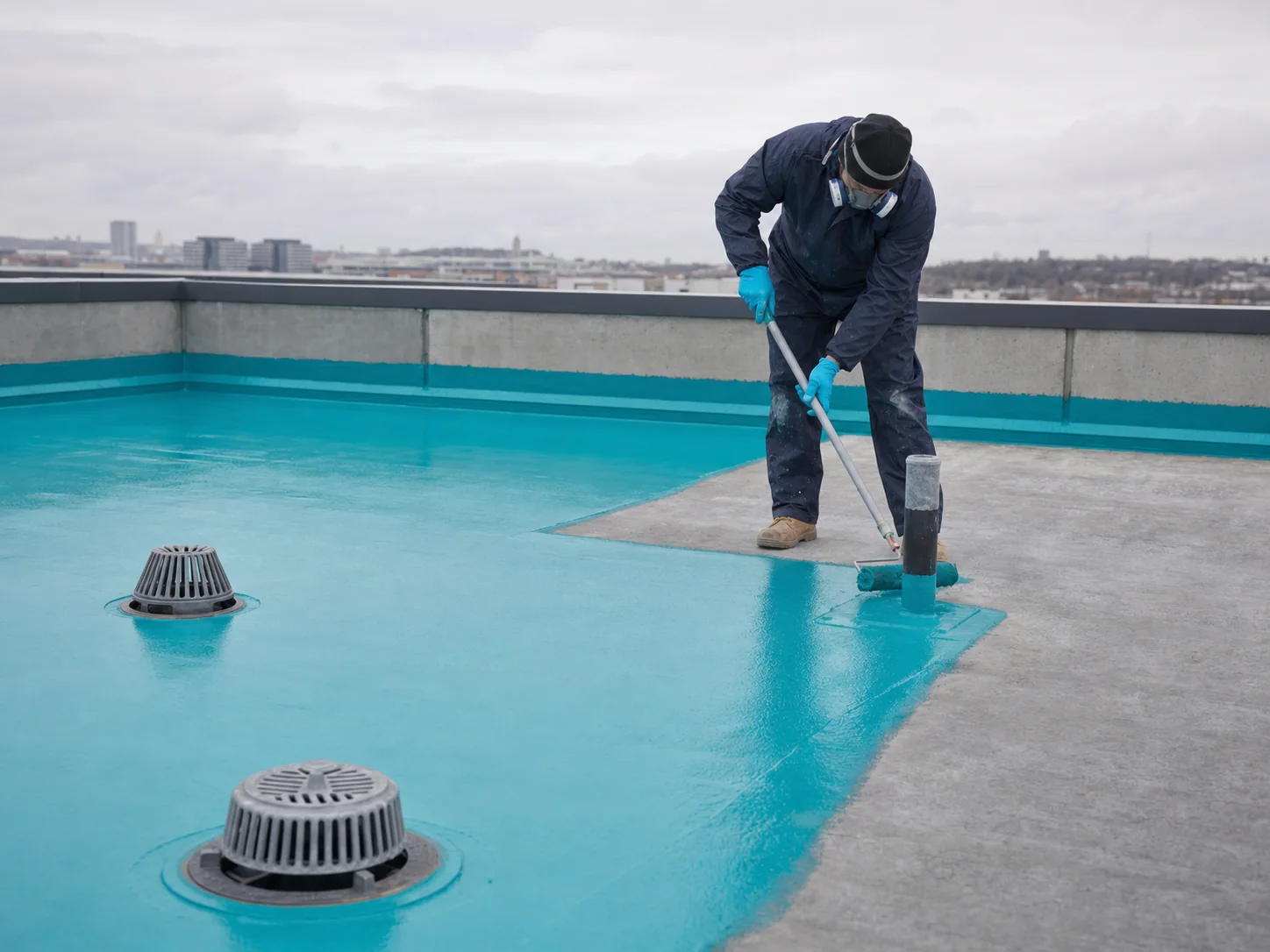 Teal waterproof membrane application around rooftop drainage details